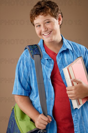 Studio portrait of boy (12-13) with backpack and books. Photo : Rob Lewine