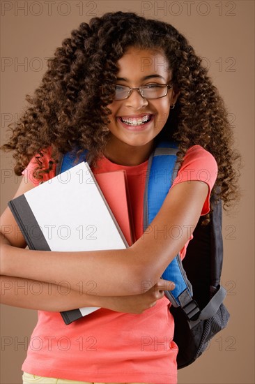 Studio portrait of girl (10-11) with backpack and books. Photo : Rob Lewine