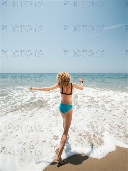Happy young woman running in to sea. Photo: Erik Isakson