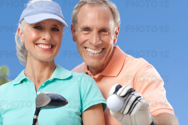Portrait of couple holding golf club and ball. Photo: db2stock