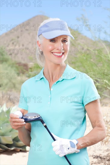 Portrait of mature woman holding golf club. Photo: db2stock