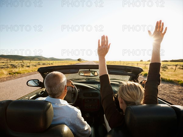 USA, Utah, Kanosh, Mad-adult couple driving through desert plains in convertible car. Photo: Erik Isakson