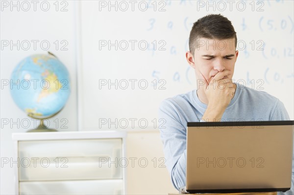 Teenage (16-17) student using laptop.