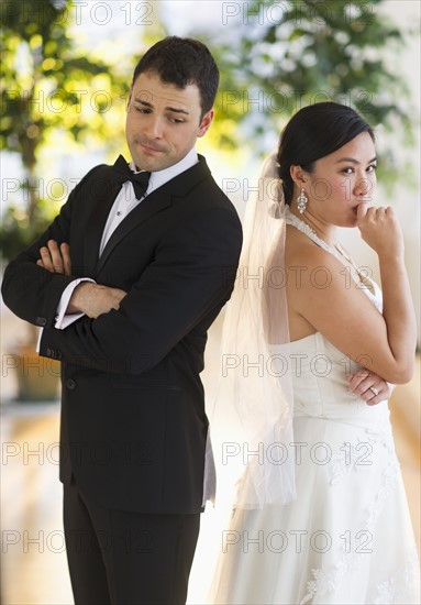 Bride and groom looking nervous standing back to back.