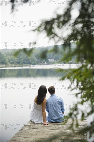 USA, New York, Putnam Valley, Roaring Brook Lake, Couple sitting on pier by lake. Photo: Jamie Grill