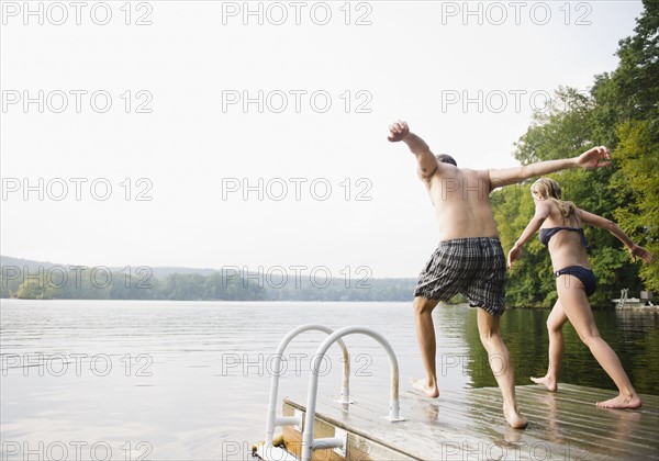 USA, New York, Putnam Valley, Roaring Brook Lake, Couple about to jump from pier to lake. Photo: Jamie Grill