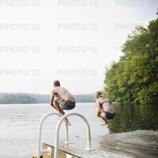 USA, New York, Putnam Valley, Roaring Brook Lake, Couple jumping from pier to lake. Photo: Jamie Grill