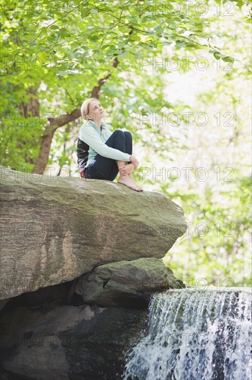 USA, New York, New York City, Manhattan, Central Park, Young woman sitting on rock. Photo : Daniel Grill