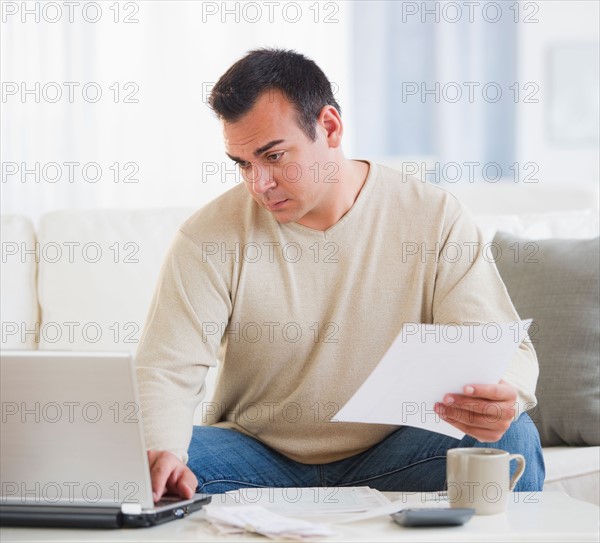 Portrait of man doing paperwork in living room. Photo: Daniel Grill