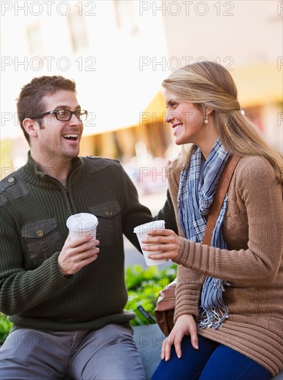 Young couple sitting with take-away coffee. Photo: Daniel Grill