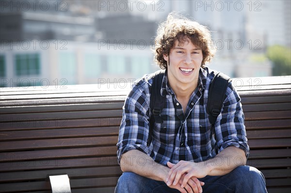 USA, Washington, Seattle, Young man sitting on bench. Photo: Take A Pix Media