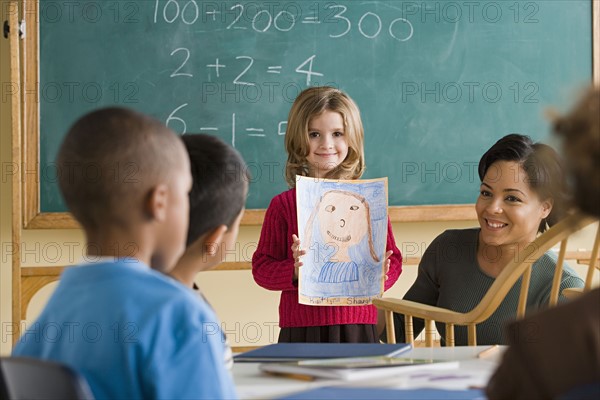 Girl (6-7) showing her drawing in classroom. Photo : Rob Lewine