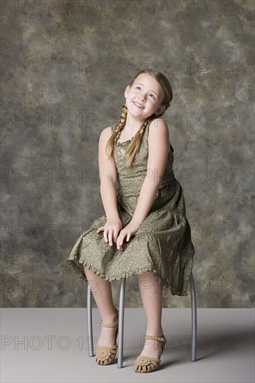 Portrait of smiling girl (8-9) sitting on stool. Photo: Rob Lewine