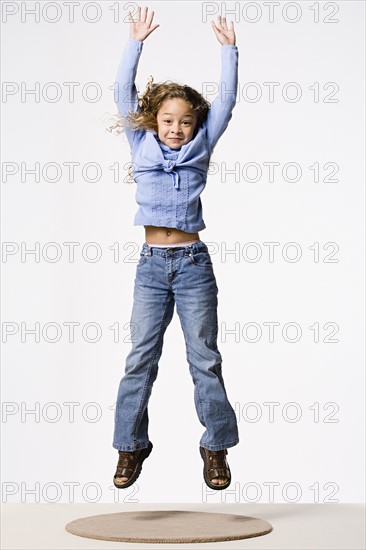 Smiling girl (8-9) jumping, studio shot. Photo: Rob Lewine
