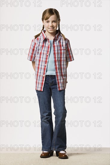 Portrait of smiling girl (8-9) wearing checked shirt, studio shot. Photo: Rob Lewine
