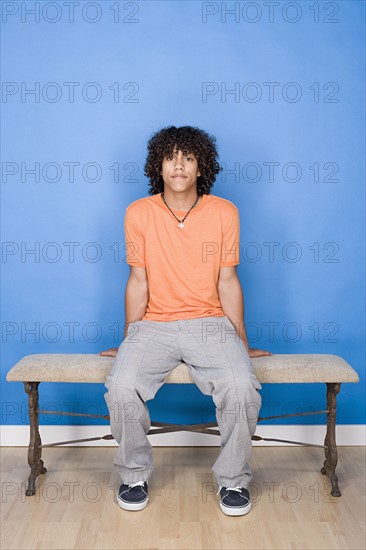 Portrait of teenage boy (14-15) sitting on bench. Photo: Rob Lewine