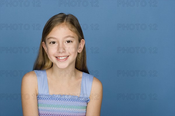 Portrait of happy girl (8-9) n blue background. Photo: Rob Lewine