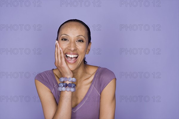 Portrait of smiling woman sitting on purple background, studio shot. Photo: Rob Lewine