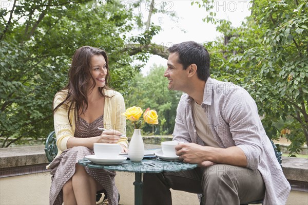 Happy couple sitting at table at outdoor cafe. Photo: Tetra Images