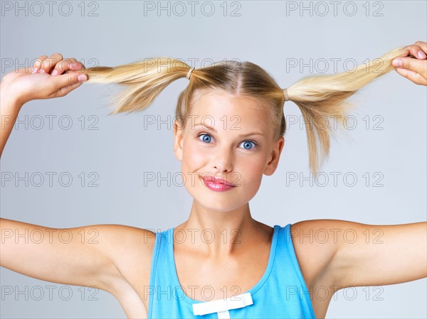 Studio portrait of young woman with hand in hair. Photo : Yuri Arcurs