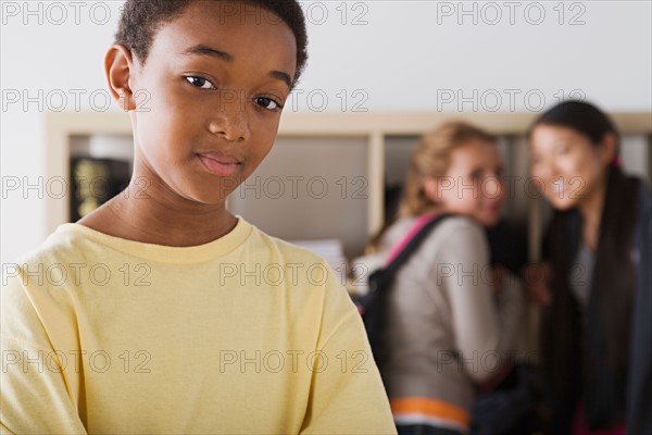 Portrait of schoolboy with two gild gossiping in background. Photo : Rob Lewine