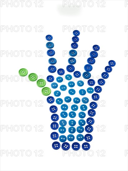 Studio shot of blue and green buttons arranged in human hand. Photo : David Arky
