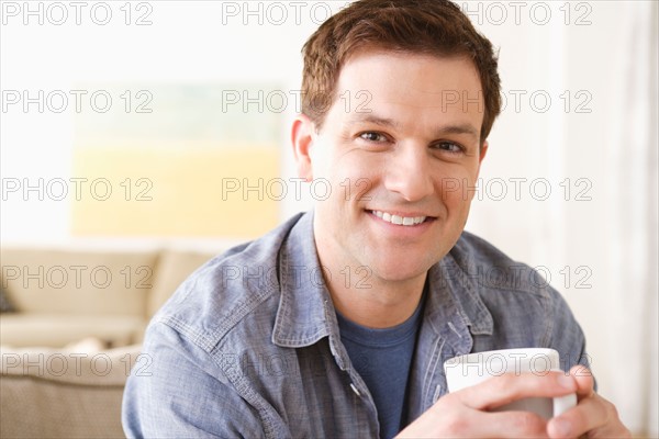 Portrait of smiling mid adult man holding mug. Photo : Rob Lewine