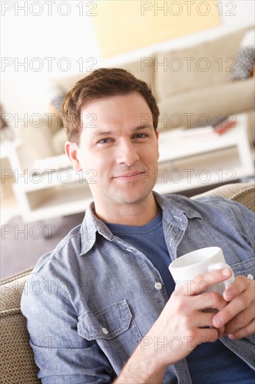 Portrait of smiling mid adult man holding mug. Photo : Rob Lewine