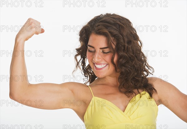 Portrait of young woman showing her biceps, studio shot. 
Photo: Daniel Grill