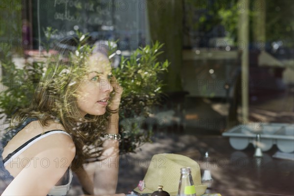 Holland, Amsterdam, Woman in cafe talking mobile phone. 
Photo : Jan Scherders