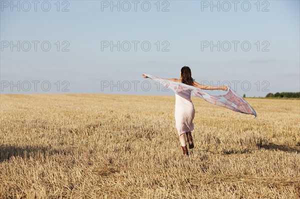 France, Picardie, Albert, Young woman running through stubble with shawl. 
Photo : Jan Scherders