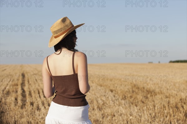 France, Picardie, Albert, Young woman in straw hat looking at country landscape. 
Photo: Jan Scherders