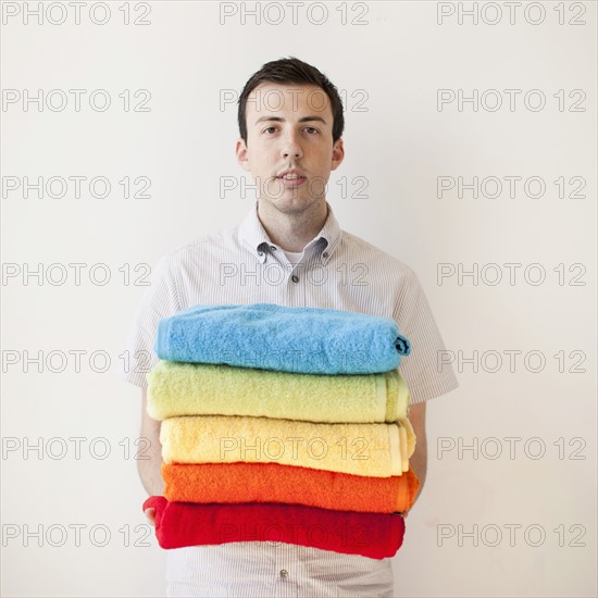 Young man holding stack of multi-coloured towels. 
Photo: Jessica Peterson