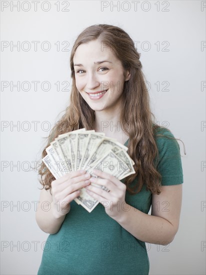 Attractive young woman holding fan made up from us dollar banknotes. 
Photo: Jessica Peterson