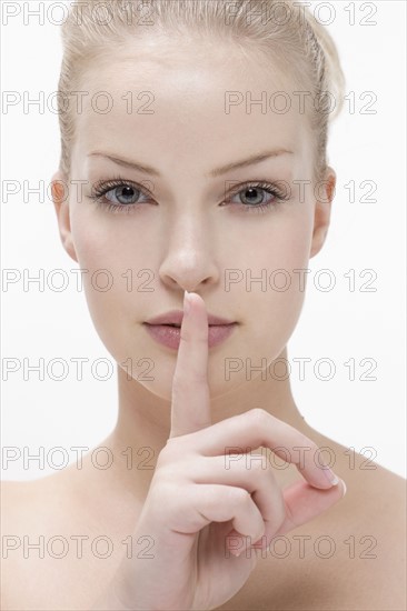 Young woman pressing finger against mouth. Photo: Jan Scherders