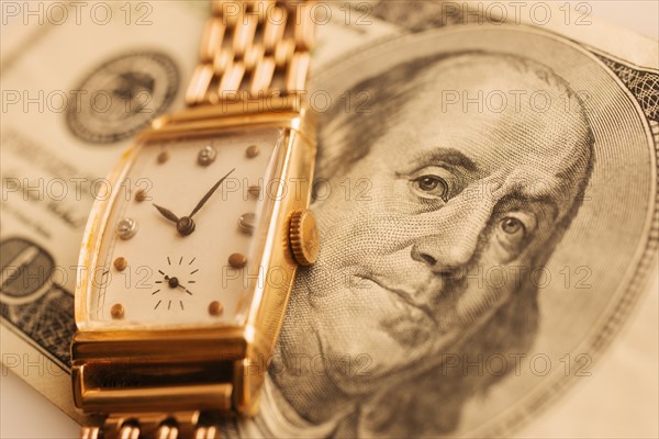Studio shot of banknote and gold watch.