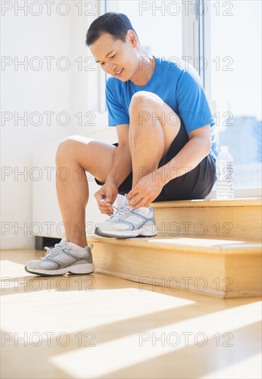 Mid adult man lacing his running shoes. Photo: Daniel Grill