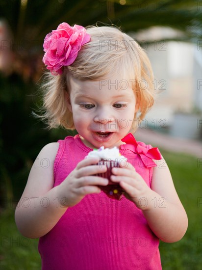 Girl with blong hair looking at cupcake. Photo: Jessica Peterson