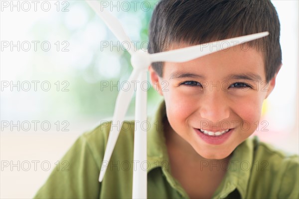 Portrait of boy (6-7) holding scale model of wind turbine.