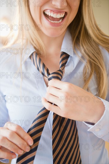 Close up of laughing young woman tying tie