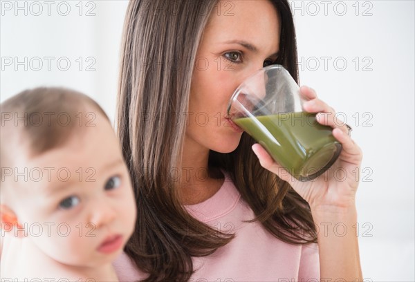 Mother with daughter (6-11 months) drinking vegetable smoothie