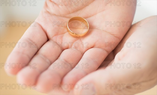 Hand holding wedding ring.