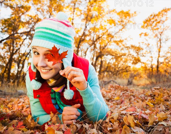 Portrait of smiling young woman lying on autumn leaves . Photo : Mike Kemp