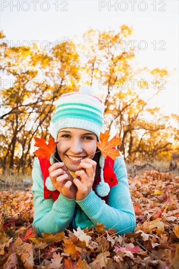 Portrait of smiling young woman lying on autumn leaves . Photo : Mike Kemp