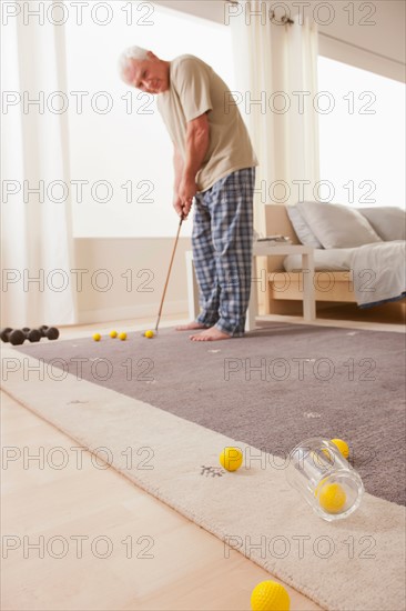 Senior man playing mini golf at home. Photo: Rob Lewine