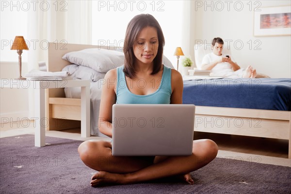 Woman using laptop with husband on lounger in background. Photo: Rob Lewine