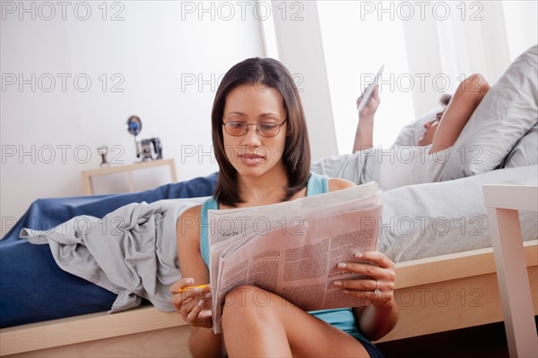 Woman doing crosswords in newspaper and man reading in bed. Photo: Rob Lewine