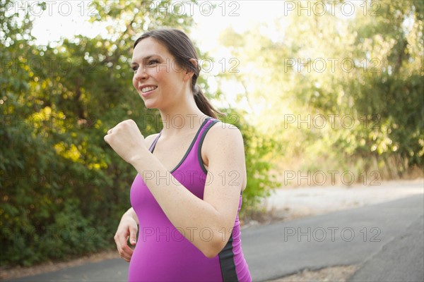 Pregnant mid adult woman in sport clothing jogging. Photo : Jessica Peterson