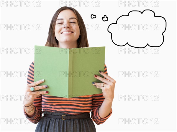 Studio shot young woman holding book with thought bubble next to. Photo : Jessica Peterson
