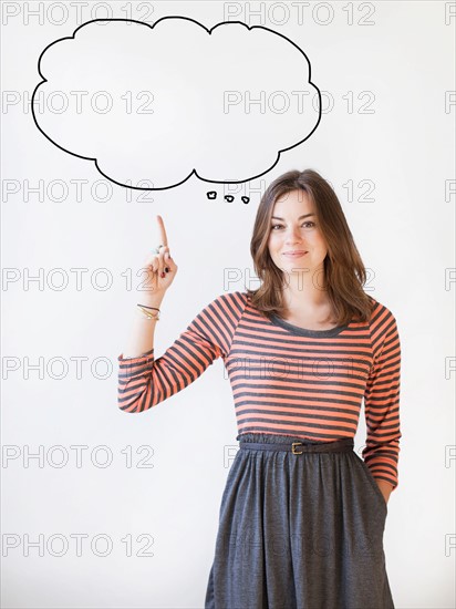 Studio shot young woman pointing up on thought bubble. Photo : Jessica Peterson
